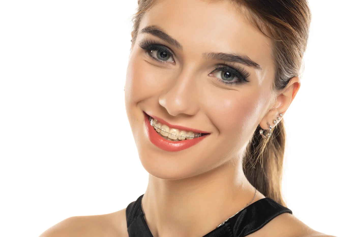 Smiling woman with braces wearing earrings and a dark top
