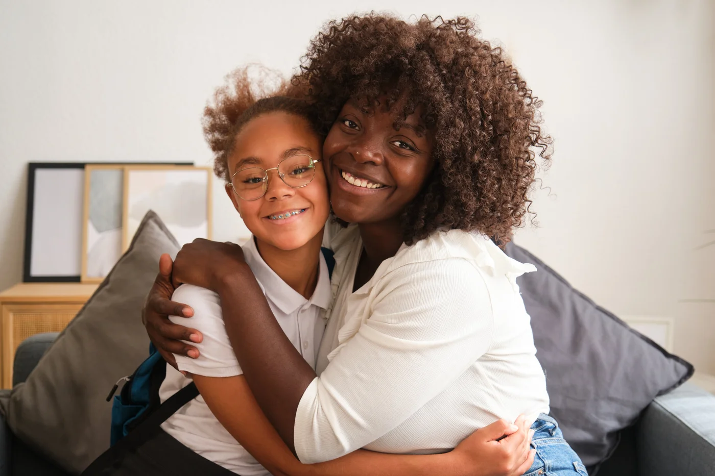 A child with glasses smiling with a parent at home