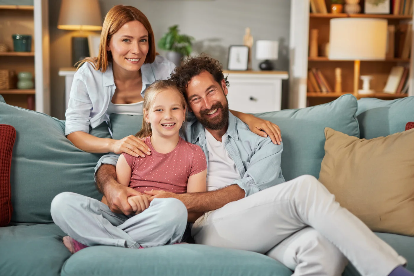 Two parents and a child smiling together on a sofa