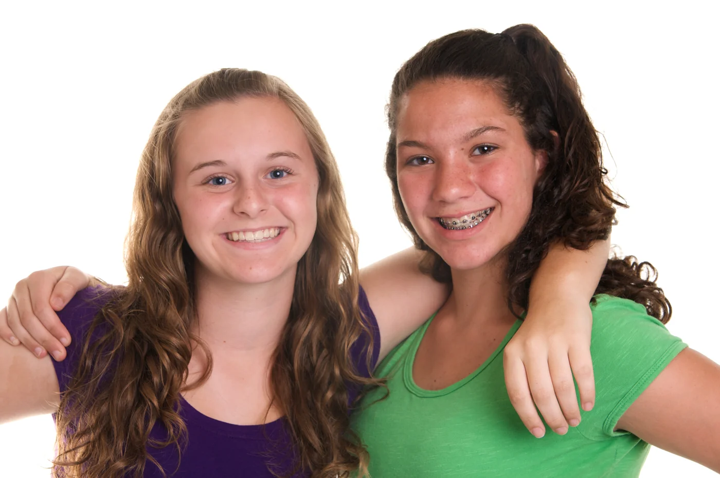 Two girls smiling together, one wearing braces